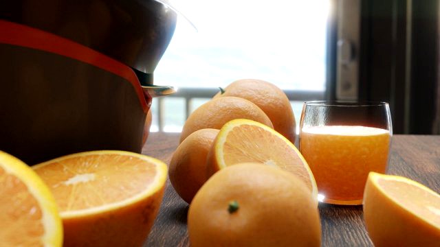 Citrus juicer with oranges and a glass of juice