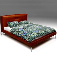 Brown leather bed with metal legs and bed linen with ethnic pattern