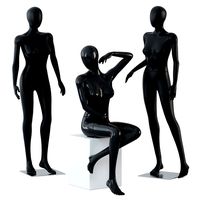 Two female mannequins stand and one sits on a white square stool 58