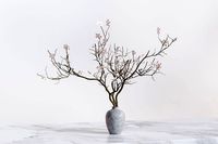 Twig with flowers and a bird in ceramic vase